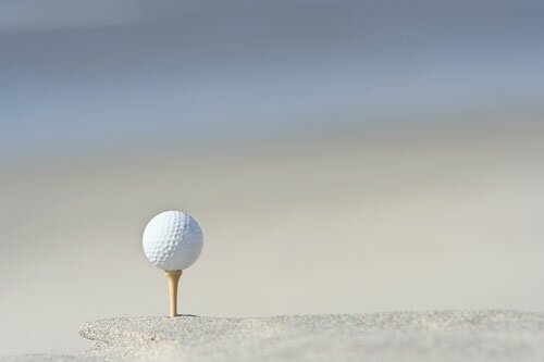 Golf ball on tee in sand trap
